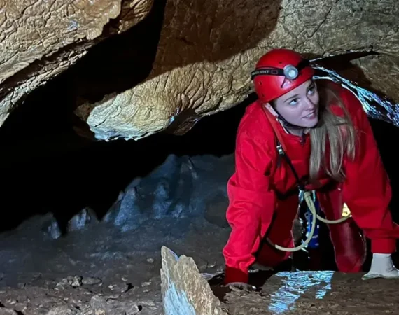 junge Frau in einer Höhle mit Sicherheitsausrüstung