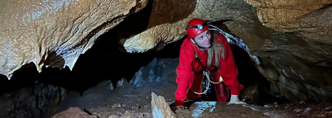 junge Frau in einer Höhle mit Sicherheitsausrüstung