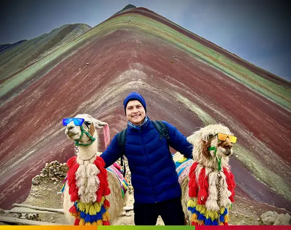 Persönlicher Besuch an der Rainbow Mountain Peru (Vinicunca) – Reisender mit Lamas vor der berühmten Siebenfarben-Berglandschaft in den peruanischen Anden.
