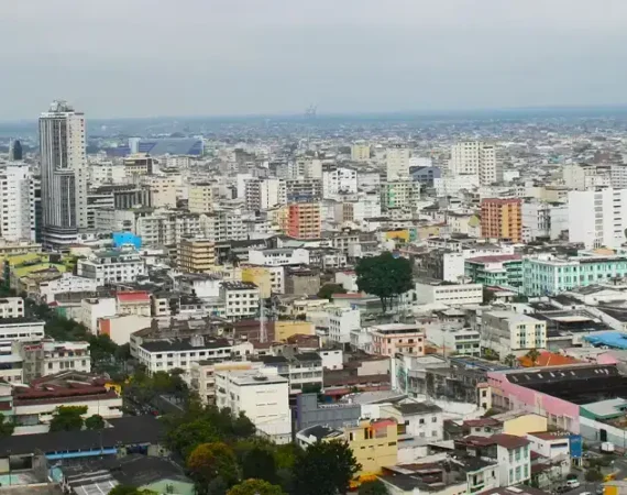 Panoramablick auf das Stadtzentrum von Guayaquil mit modernen Gebäuden und bewölktem Himmel.