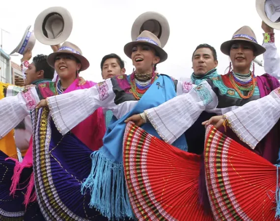 Traditionelle Tänzer*innen in farbenfrohen Trachten während der Fiesta de la Mama Negra in Latacunga, Ecuador.