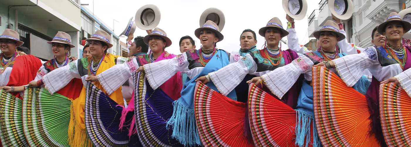 Traditionelle Tänzer*innen in farbenfrohen Trachten während der Fiesta de la Mama Negra in Latacunga, Ecuador.