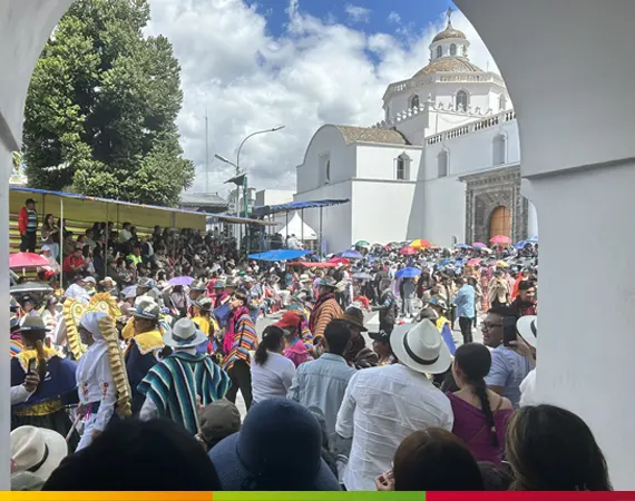 Menschenmenge und farbenfroher Umzug der Fiesta de la Mama Negra vor einer historischen Kirche in Latacunga, Ecuador.