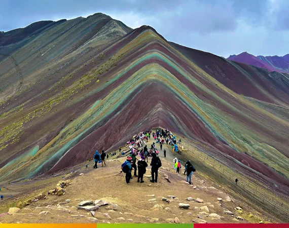 Besucher auf dem Hauptgrat der Rainbow Mountain Peru (Vinicunca) – Blick auf die markanten farbigen Schichten des Berges der sieben Farben in den peruanischen Anden.